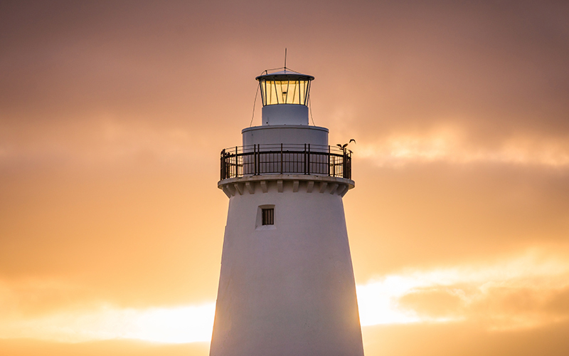lighthouse at sunset - the Hamptons Group chose the lighthouse to represent its alrernatice invesement firm