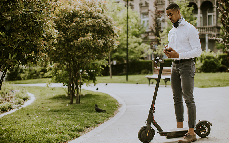Image of a young college student on an electric scooter - electric vehicles help corporations reach sustainability.