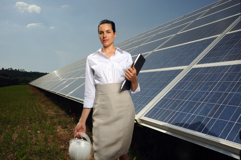  A business woman investor examines solar panels while holding her notebook with social venture capital impacts listed.
