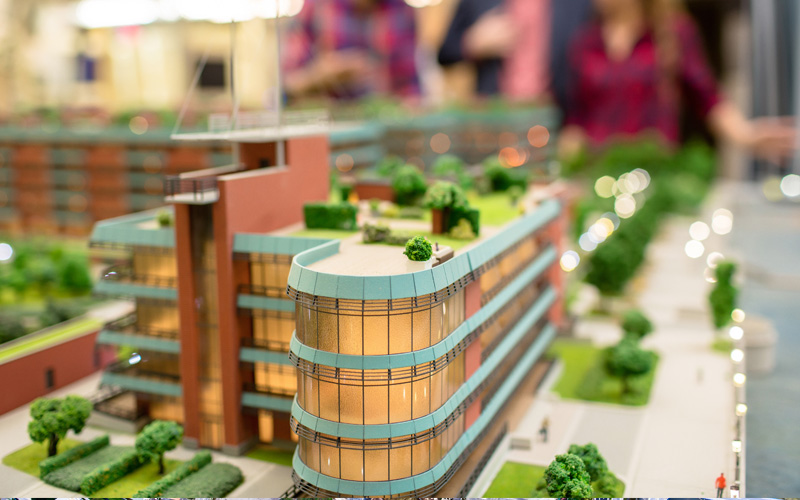 Image of a diorama of a real estate investment project with advisors out of focus in the background.